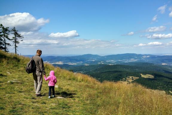 Mężczyzna z plecakiem i małe dziecko idą ścieżką w górach