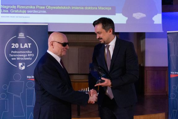 RPO Marcin Wiącek wręcza statuetkę nagrody Markowi Kalbarczykowi