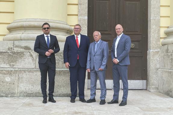 Cztery osoby pozują do wspólnego zdjęcia przed wejściem do zabytkowego budynku