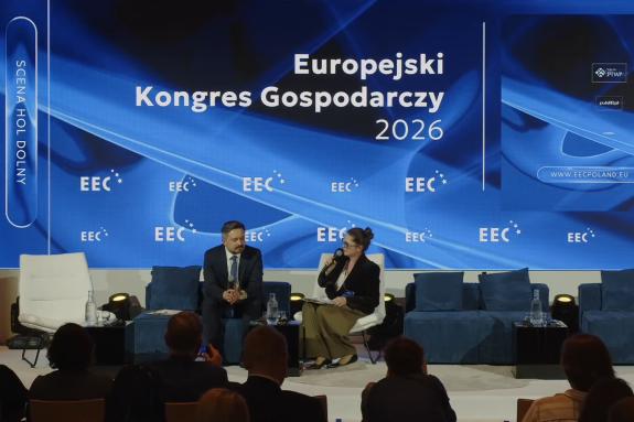Dwie osoby siedzą na fotelach na scenie i rozmawiają, w tle duża plansza z napisem "Europejski Kongres Gospodarczy 2026"