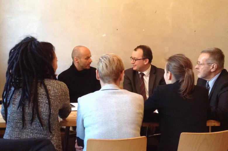  Zdjęcie: rzecznik Bodnar i Marek Piekarski zwróceni do siebie twarzami siedzą przy stola razem z czterema innymi osobami