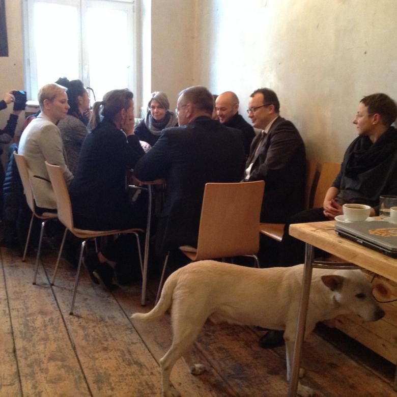 Zdjęcie: rozmowa przy stole, a na pierwszym planie - biały pies