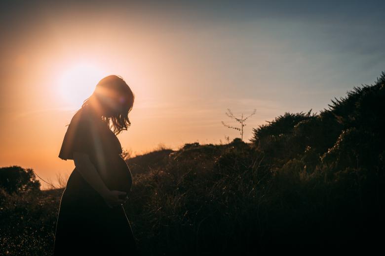 kobieta w ciąży na tle zachodzacego słońca