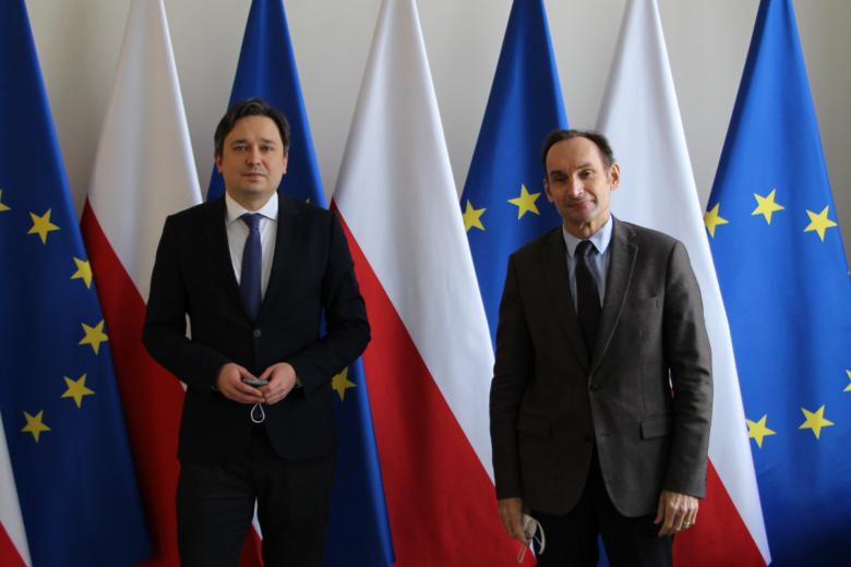 dwóch mężczyzn pozujących na tle flag Polski i Unii Europejskiej