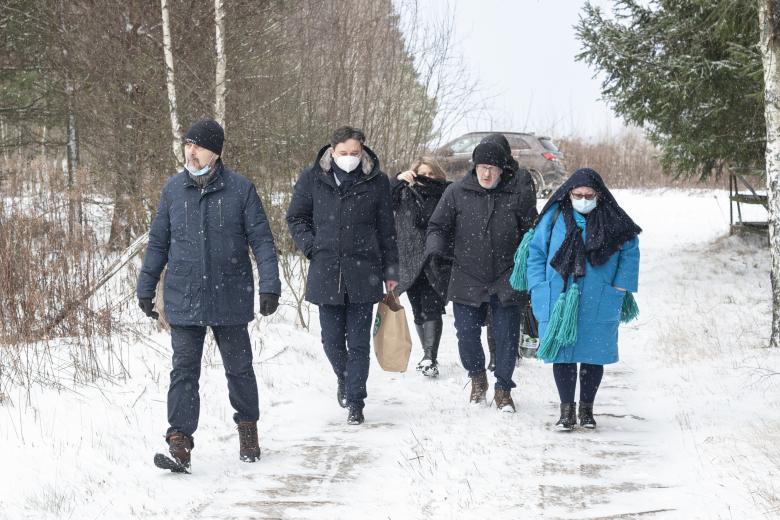 Grupa osób niesie artykuły pierwszej potrzeby gruntową, zaśnieżoną drogą