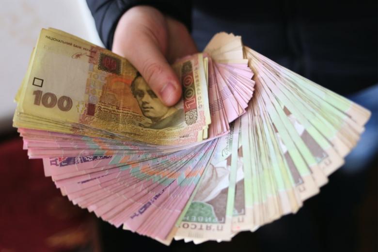 ręka trzymająca plik baknotów ukraińskiej waluty - hrywny