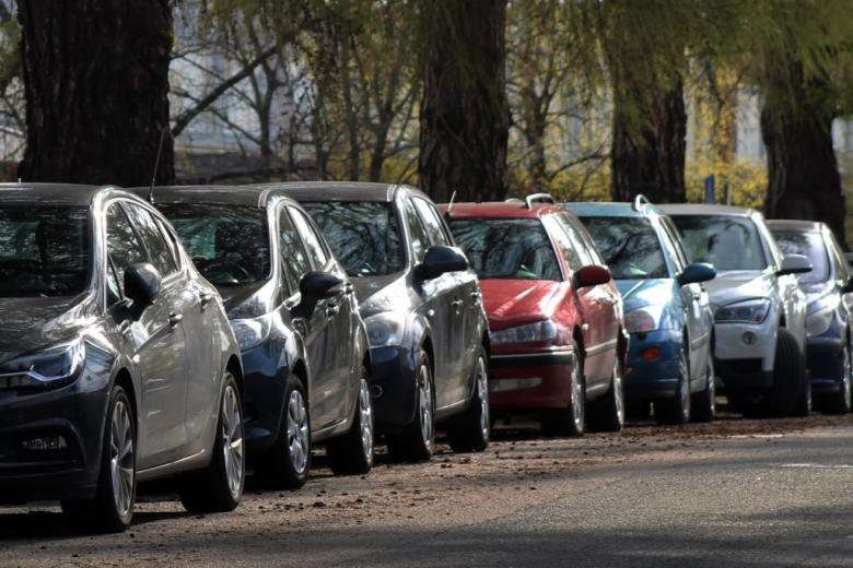 rząd kilkunastu samochodów zaparkowanych wzdłuż ulicy