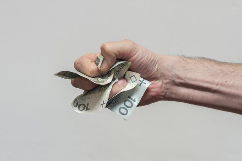 ręka ściskająca polskie banknoty 