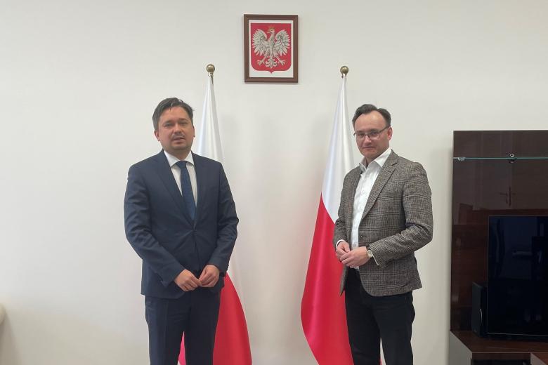 RPO Marcin Wiącek oraz rzecznik praw dziecka pozują na tle flag i godła Polski