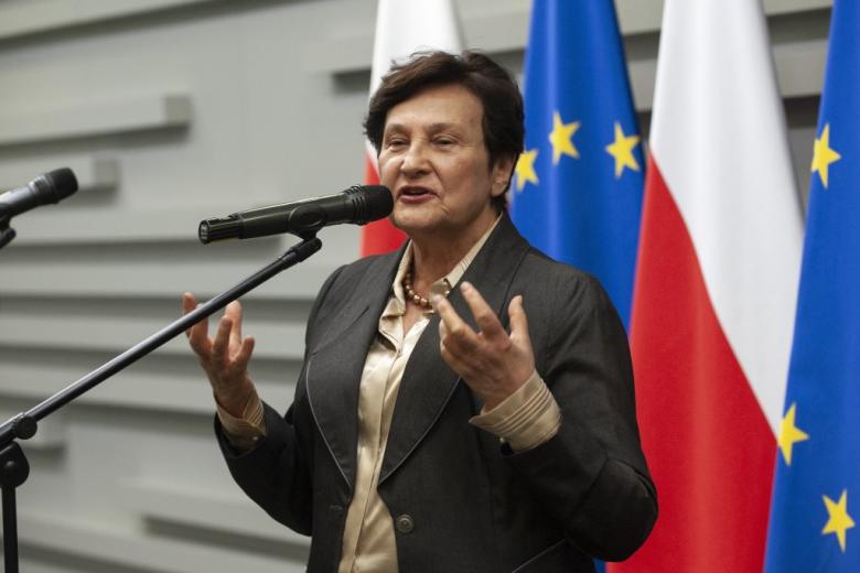 ZRPO Hanna Machińska przemawiająca do mikrofonu na tle flag Polski i UE
