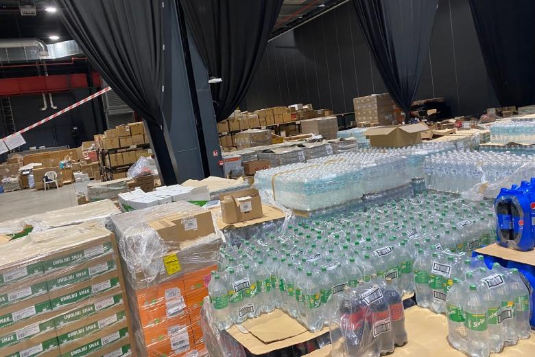 Magazyn w hali Global EXPO, widać zgrzewki z wodą i napojami, pudełka