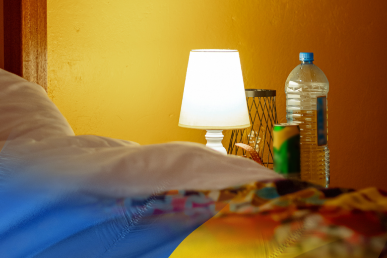 zdjęcie zasłanego łóżka z lampką nocną 