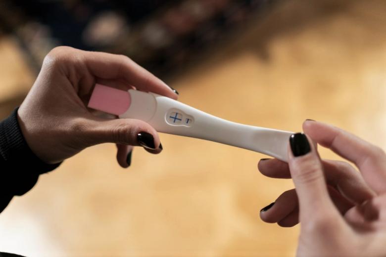 osoba spogląda na test ciążowy
