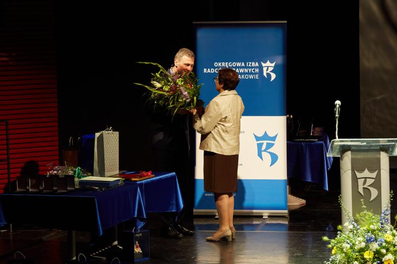 ZRPO Hanna Machińska wręcza bukiet kwiatów dziekanowi Okręgowej Izby Radców Prawnych na scenie