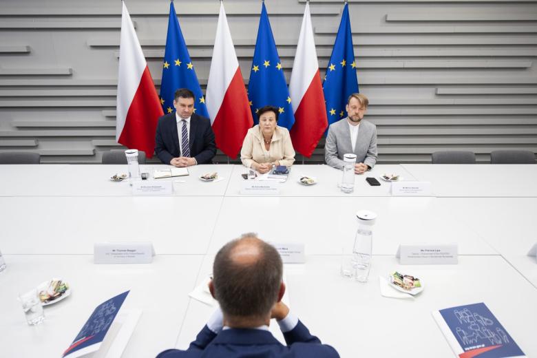ZRPO Hanna Machińska, Mirosław Wróblewski i Marcin Sośniak siedzący za stołem na tle flag Polski i UE
