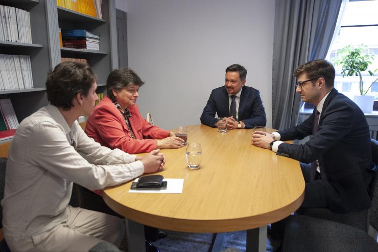 RPO Marcin Wiącek, ZRPO Valeri Vachev i ambasador wraz z pracownikiem ambasady rozmawiają przy stole w gabinecie. Za plecami ambasador znajduje się regał z książkami.