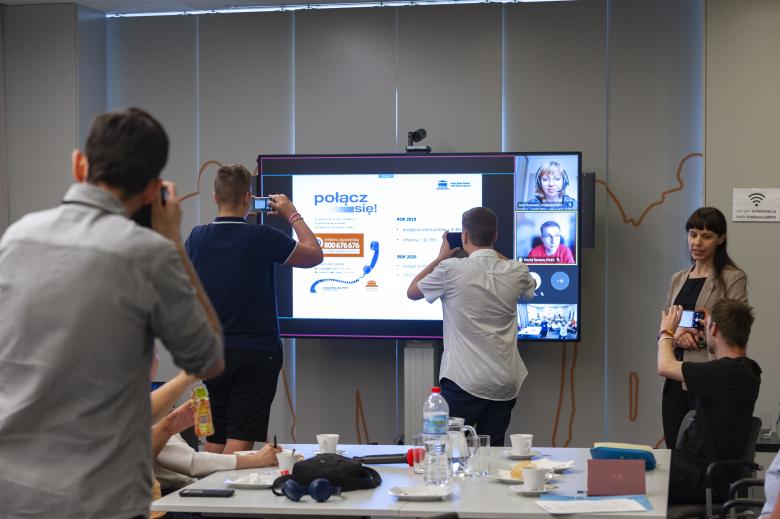 Uczestnicy warsztatu robią zdjęcie slajdu prezentacji wyświetlanego na monitorze