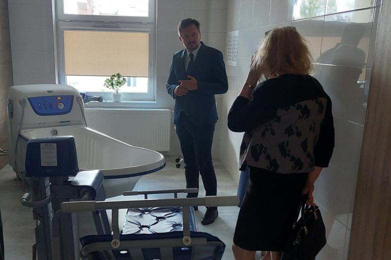 RPO Marcin Wiącek rozmawia z pracownicą hospicjum stojąc w pomieszczeniu ze sprzętem medycznym