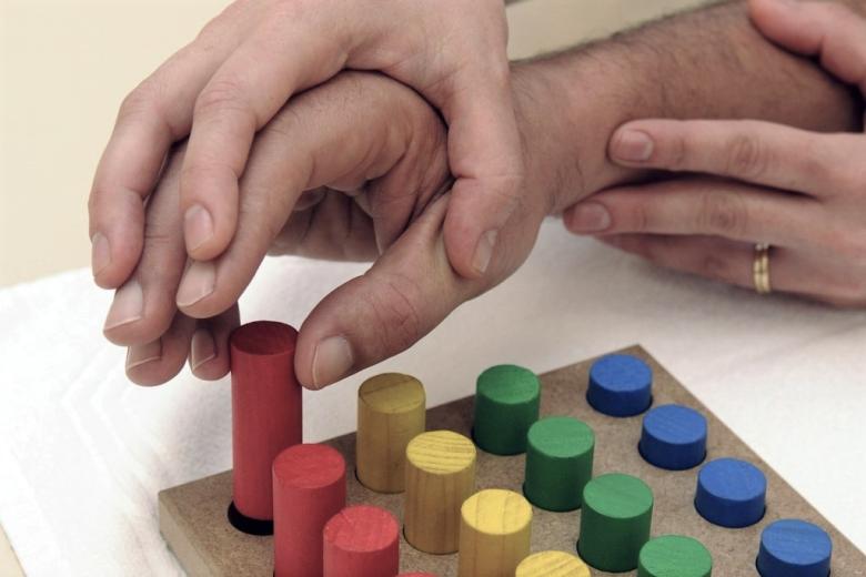 zdjęcie ręki dziecka, które z pomocą dorosłego wkłada kolorowe  kredki we właściwe miejsca 