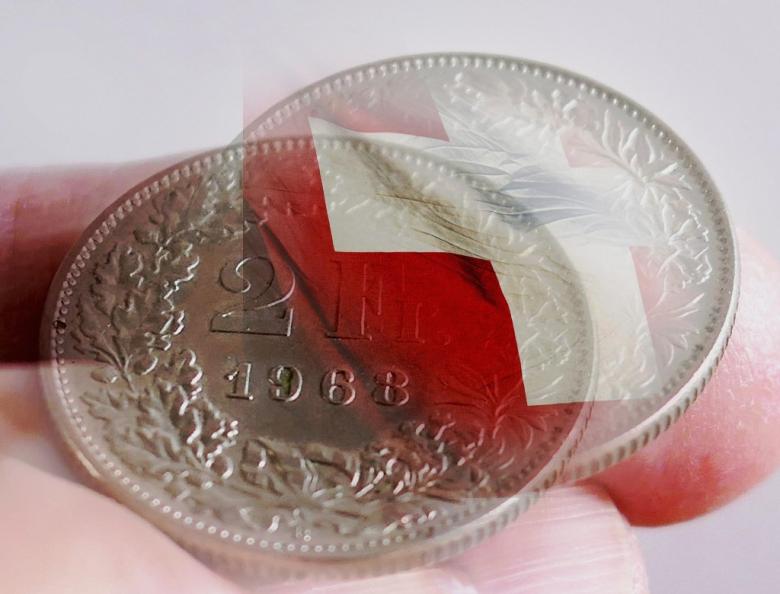 moneta frankowy na tle flagi szwajcarskiej  