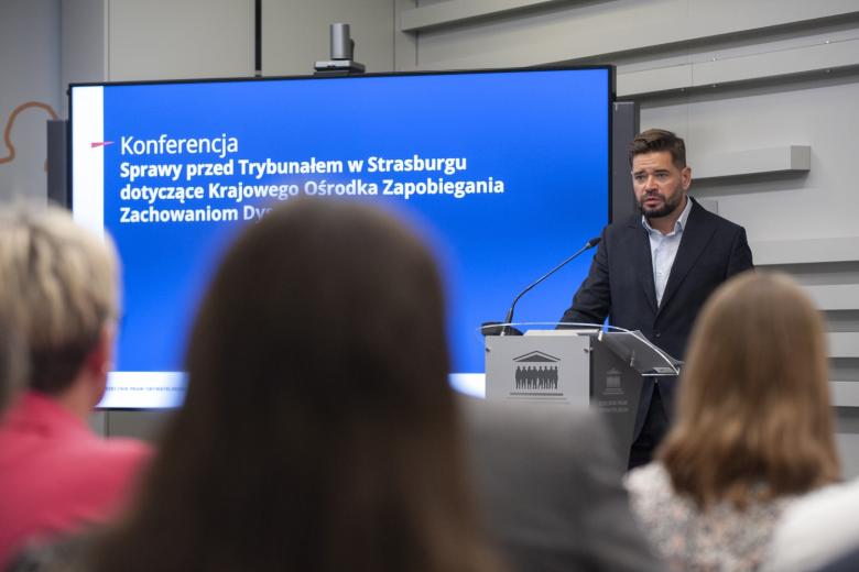 prof. Michał Królikowski stoi za mównicą i wygłasza wystąpienie na konferencji
