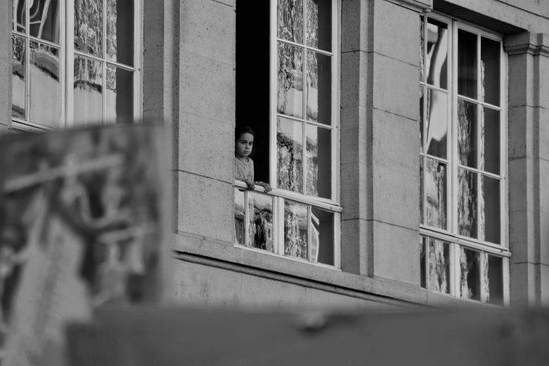 Czarno białe zdjęcie z dzieckiem wyglądającym przez okno