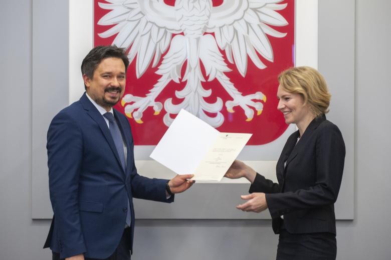 RPO wręcza akt powołania Joannie Lipnickiej na tle godła Polski