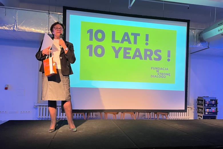 ZRPO Hanna Machińska przemawia stojąc na scenie na tle telebimu z napisem "10 lat! 10 years! Fundacja W Stronę Dialogu" 