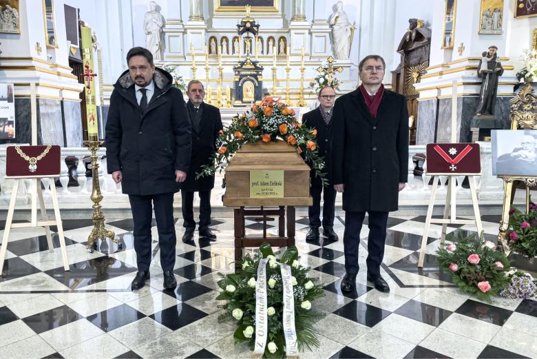 Cztery osoby stoją obok trumny stojącej na podwyższeniu w kościele. Na trumnie tabliczka z napisem "ś.p. prof. Adam Zieliński, żył 91 lat, zm. 15.XI.2022 r."