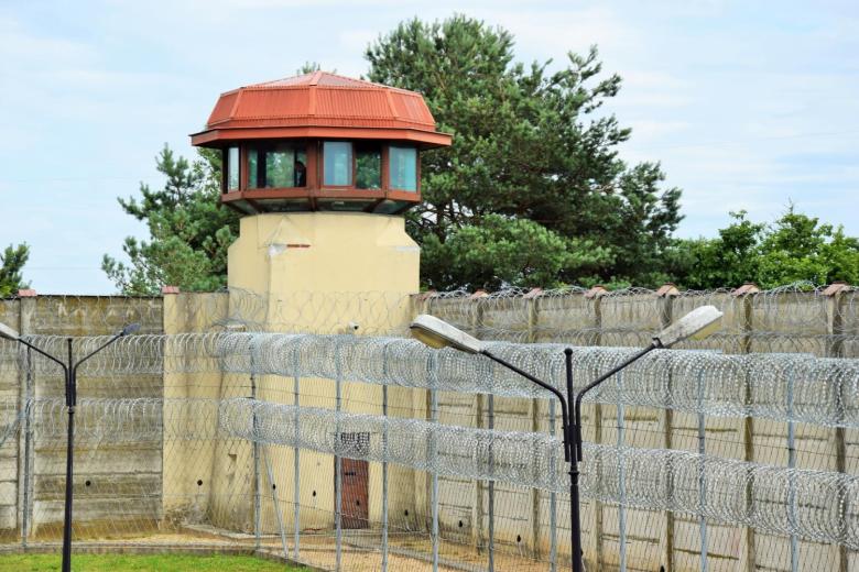 Wieżyczka strażnicza i ogrodzenie z drutem kolczastym okalające plac w areszcie śledczym
