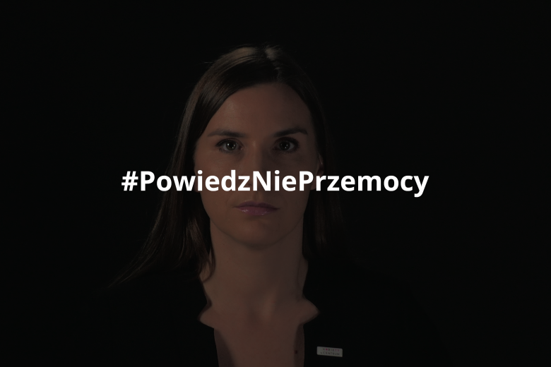Magdalena Sobkowiak stojąca na czarnym tle i spoglądająca w obiektyw. Na obraz nałożony jest hashtag "Powiedz Nie Przemocy"