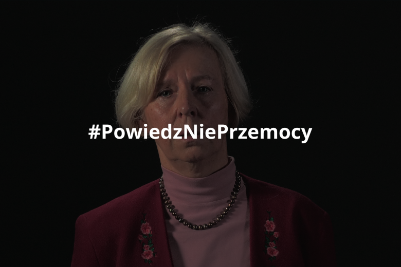 Urszula Nowakowska stojąca na czarnym tle. Na obraz nałożony jest hashtag "Powiedz Nie Przemocy"