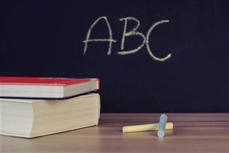 książki i kredki na tle szkolnej tablicy z literami ABC
