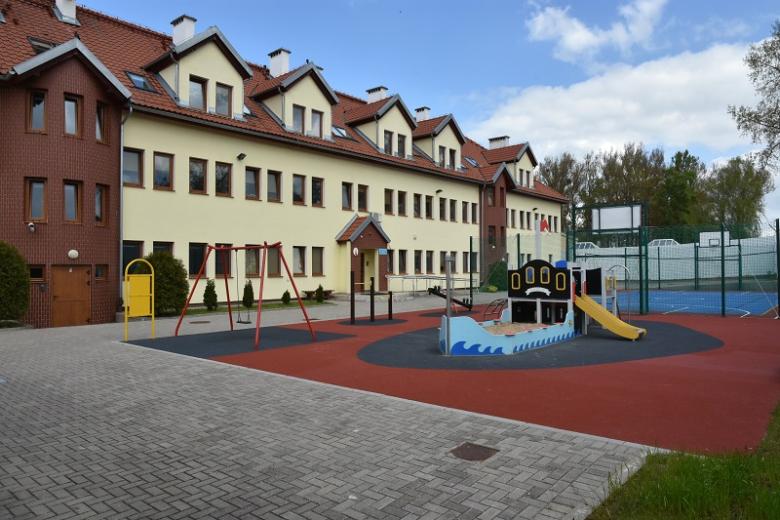 Plac zabaw dla dzieci przed dwupiętrowym budynkiem