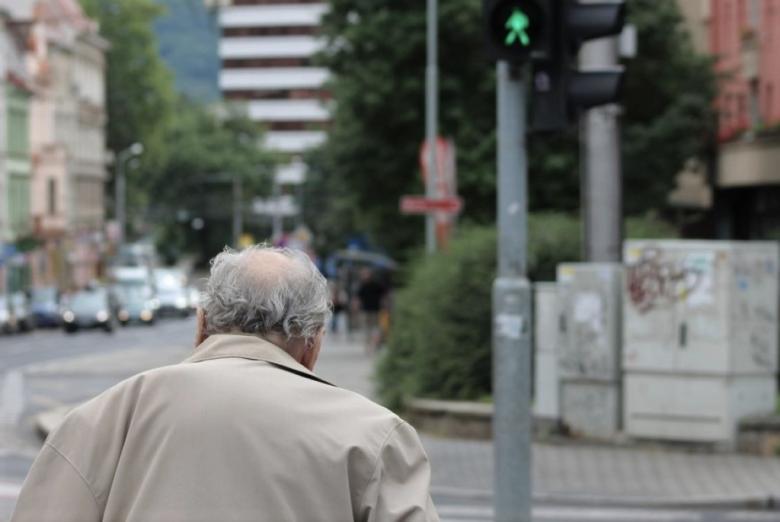 starszy człowiek przechodzi przez ulicę na zielonym świetle  