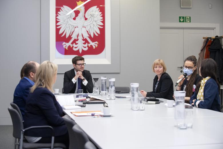 ZRPO Valeri Vachev i członkinie Inicjatywy rozmawiają siedząc przy konferencyjnym stole. W tle godło Polski