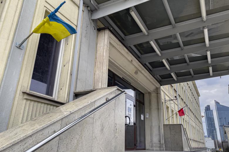 Zadaszone wejście do budynku po schodach, obok wejścia flaga Ukrainy i flaga Polski