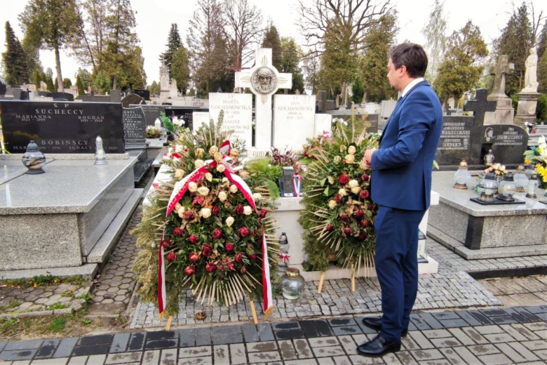 RPO Marcin Wiącek stoi przed grobem Janusza Kochanowskiego, na którym leżą wieńce i kwiaty