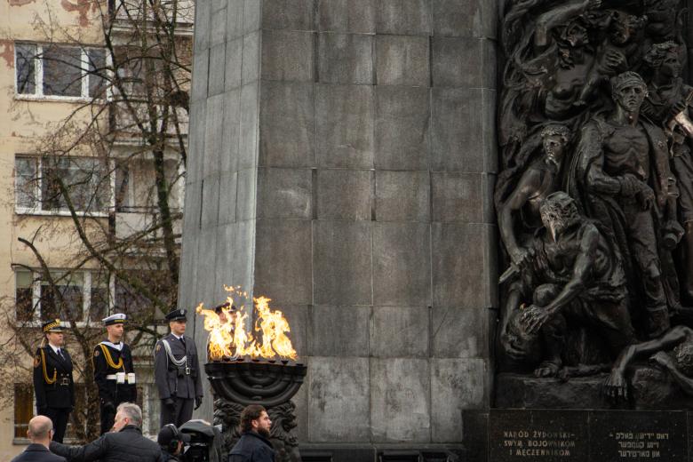 Pod pomnikiem bohaterów getta płonie menora, obok której wartę pełnią żołnierze.
