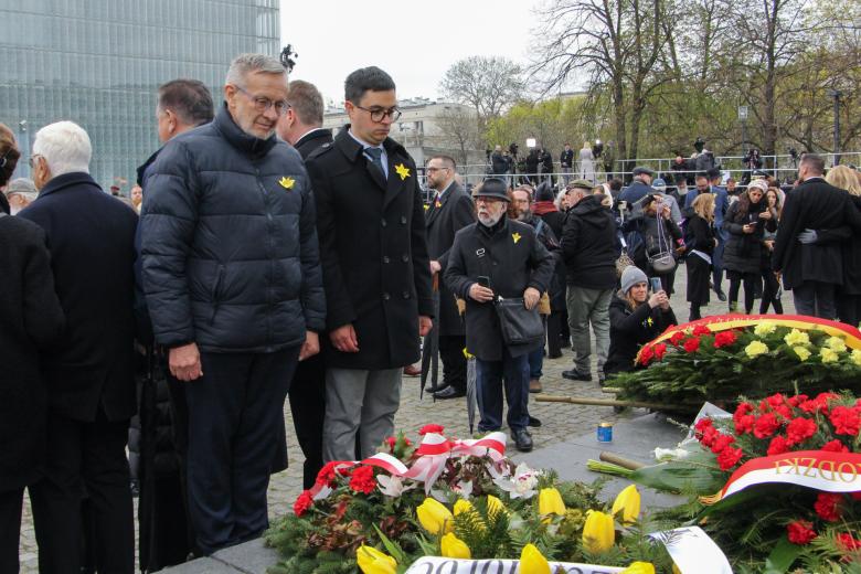 Andrzej Stefański i Michał Szwast stoją przed wieńcami złożonymi pod pomnikiem. W tle uczestnicy uroczystości.