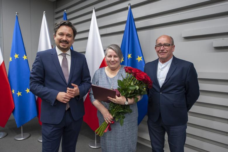 RPO Marcin Wiącek, Anna Nowak i Mieczysław Nowak pozują do wspólnego zdjęcia na tle flag Polski i UE