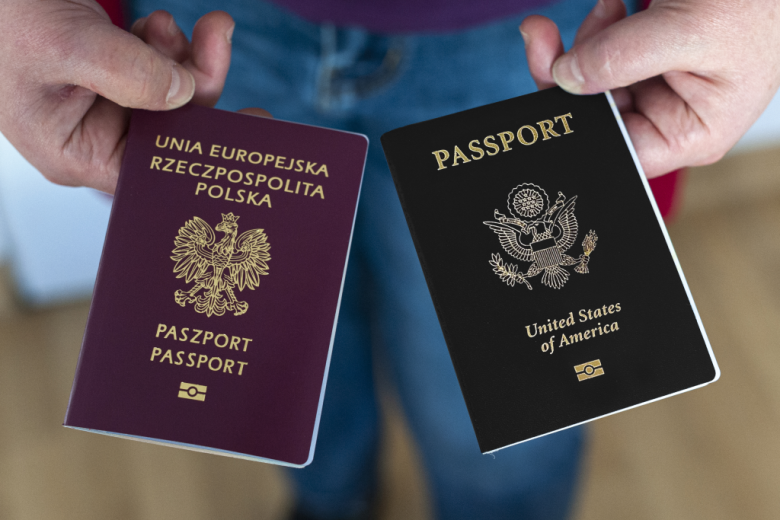 osoba trzyma  w dłoniach paszporty Polski i USA 