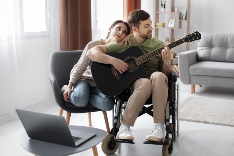 osoba na wózku gra na gitarze, inna się do niej przytula