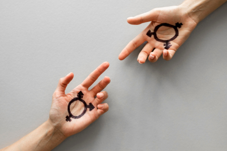 wyciągniete ku sobie dłonie z symbolami płci 