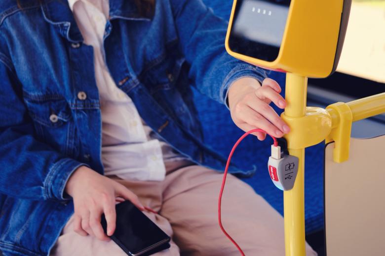 Osoba korzysta z publicznego portu ładowania telefonu przez USB w autobusie