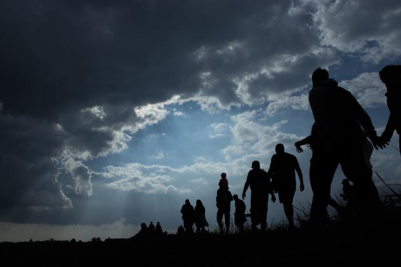 Grupa idących ludzi na tle pochmurnego nieba