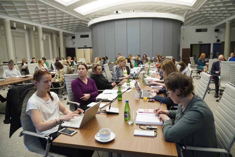 Kilkadziesiąt osób uczestniczących w szkoleniu pracuje przy stołach w dużej sali konferencyjnej 
