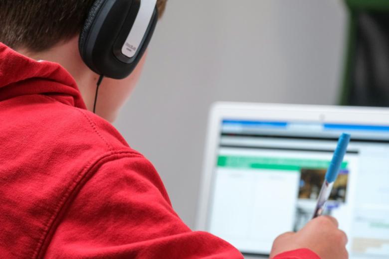 dziecko przed komputerem ze słuchawkami na uszach 