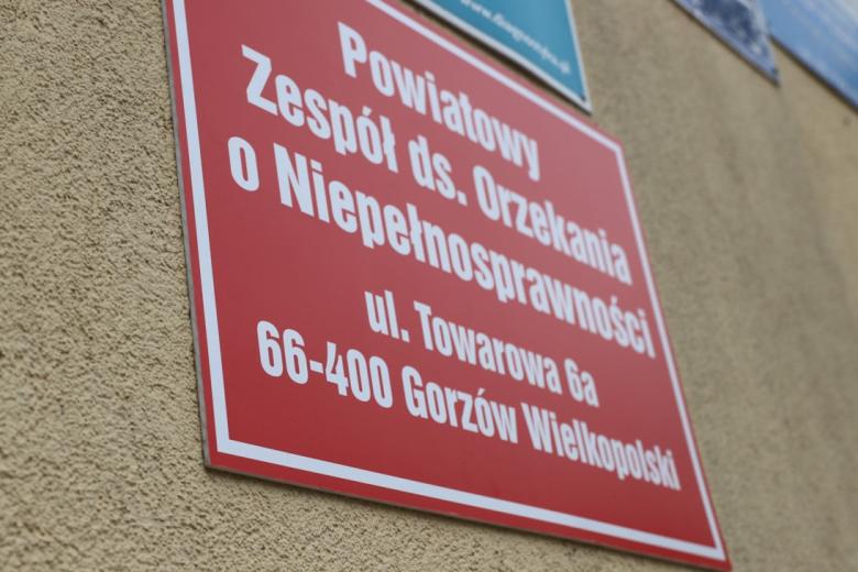 Czerwona tabliczka na budynku z napisem "Powiatowy Zespół ds. Orzekania o Niepełnosprawności"