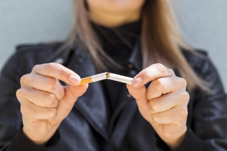 kobieta trzyma w dłoniach przełamanego papierosa 
